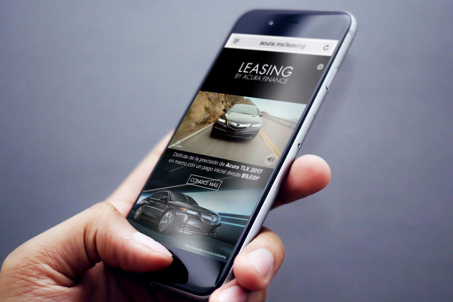 Celular en mano mostrando el sitio web de leasing Acura con un Acura TLX negro destacado, fondo gris neutro.