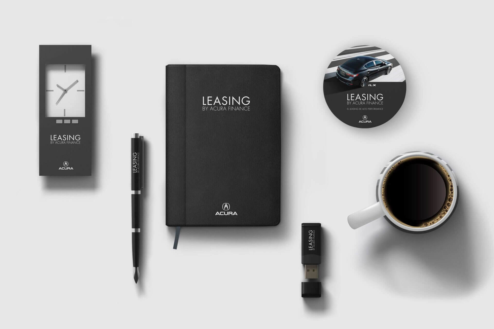 Merchandising negro de campaña Leasing Acura: cuadernillo, pluma, taza, reloj y memoria USB dispuestos elegantemente.